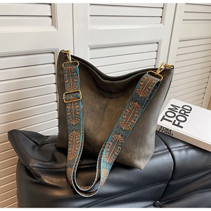 Detail of grey suede hobo bag with ethnic geometric patterns on wide shoulder strap