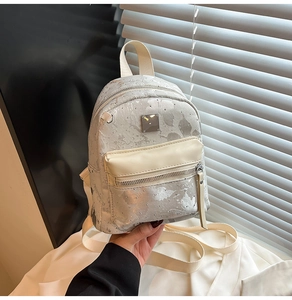 Close-up of a stylish mini backpack in silver-grey with metallic accents and leather straps