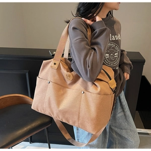 Close-up of khaki canvas travel duffel bag with multi-pocket storage and durable strap