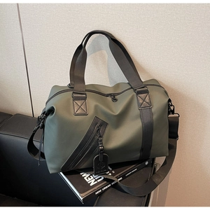 Detail of army green waterproof travel bag with black straps on a black leather sofa