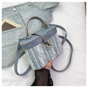 Macro detail of denim bucket bag with white floral lace patches and brown handle