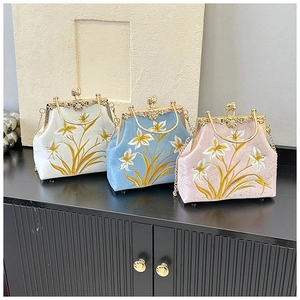 Detailed view of floral embroidery and gold metal kiss-lock clasp on canvas bags
