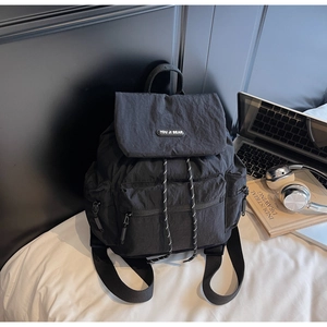 Close-up of black nylon backpack featuring a drawstring closure and logo lettering
