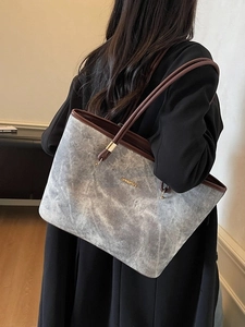 Gray marble pattern tote bag with brown leather straps worn by model against a white wall