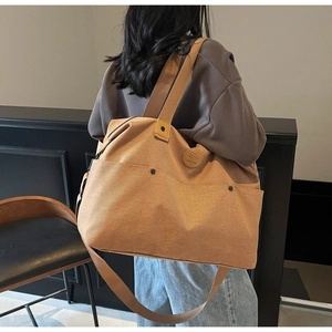 Detail of khaki canvas travel tote showing adjustable shoulder straps and top handles on model