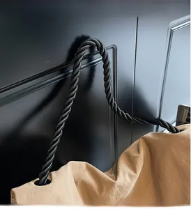 Detail of khaki tote bag featuring black braided rope handles and metallic rings