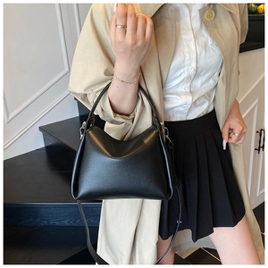 Detail of black pebbled leather handbag with top handle and slim detachable strap