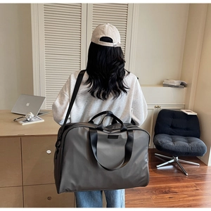 Modern grey oxford travel bag shown in use with reinforced handles and shoulder strap