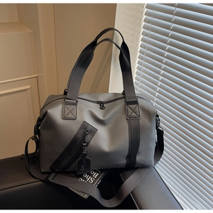 Close-up of matte grey travel bag showing diagonal zipper pocket and black nylon straps