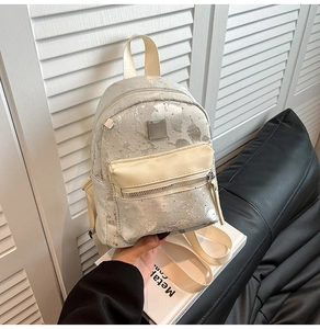 Detail of mini backpack with silver sequin texture, creamy front pocket and small studs