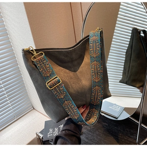 Detail of dark grey bucket bag showing geometric jacquard strap and gold metal hardware