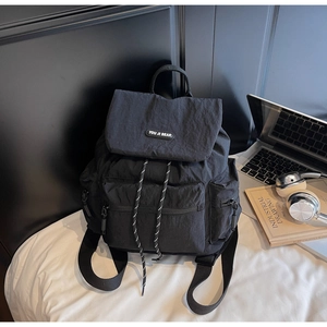 Detail of black nylon backpack with flap closure and drawstring in a lifestyle setting