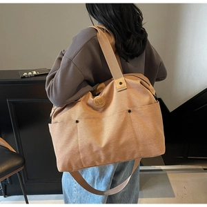 Detail of light khaki canvas tote bag showing side pocket and embossed logo on the side