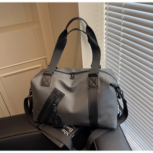 Detail of dark gray waterproof travel bag showing front zipper pocket and fabric handles