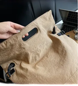 Detail of khaki tote bag with crinkled nylon fabric and metal grommet handle