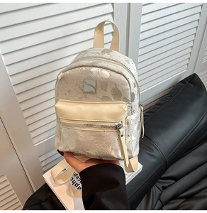 Detailed close-up of a mini silver sequin backpack with metallic texture and square metal tag