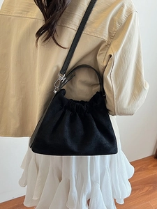 Grand sac nuage plissé noir avec cordon et boucles argentées porté par un modèle