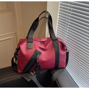 Close-up of wine red travel bag with durable black straps and large zipper pocket