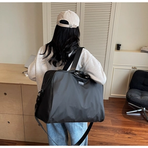 Detailed view of spacious black nylon travel tote bag shown on model for size perspective