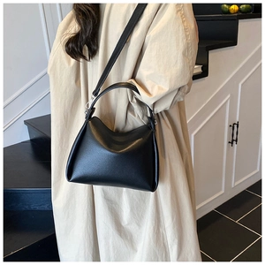 Détail d'un sac en cuir noir à grain litchi avec des boucles argentées sur la bandoulière