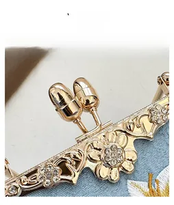 Detailed close-up of golden floral engraved clasp with rhinestones on embroidery bag