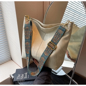 Beige leather bucket bag featuring a colorful bohemian style patterned woven strap