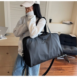 Detail of black waterproof nylon briefcase featuring leather patch and adjustable strap