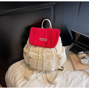 Close-up of stylish red and white nylon backpack with laptop and headphones on a desk