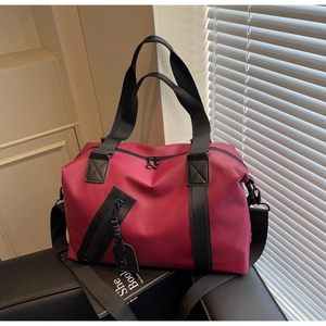 Close-up of burgundy travel bag with durable waterproof fabric and black strap details