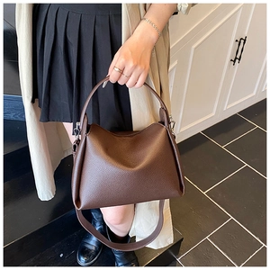 Detail of dark brown lychee leather handbag with silver hardware and shoulder strap