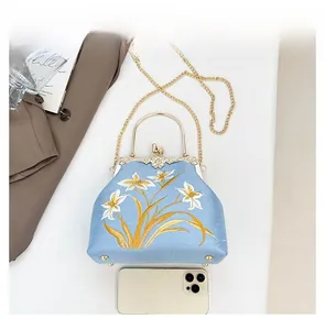 Detailed view of light blue embroidered bag showing lily pattern and size comparison