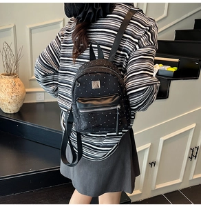 Rear view of model wearing a black mini backpack with polka dot details and zipper pocket