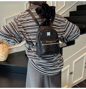 Rear view of a model wearing a black mini polka dot backpack with silver zippers