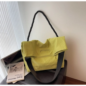 Detail view of lime green tote bag with braided black handle and wide canvas shoulder strap