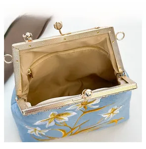 Top view of embroidered canvas kiss-lock bag showing interior lining and zipper pocket