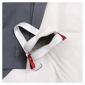 Detail of white crossbody phone bag featuring red zipper pull and gray fabric lining