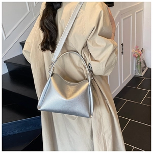 Detail of silver textured leather handbag with metallic finish and sturdy curved handle