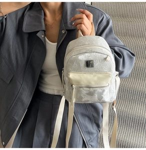 Mini silver sequin backpack held by a model in a gray suit for a stylish modern look
