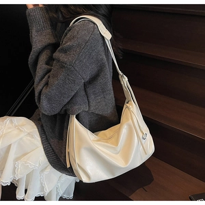 Close-up of a white leather hobo bag featuring adjustable straps and drawstring details