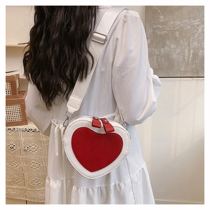 Detail view of heart shaped crossbody bag with red heart patch and white wide strap
