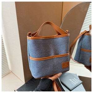 Détail du sac seau en denim bleu avec finitions en simili cuir marron et métal doré