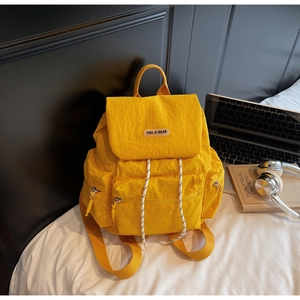 Detail of a bright yellow nylon backpack featuring multiple pockets for student commute