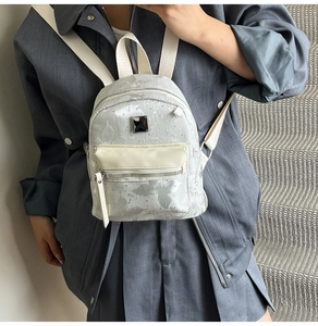 Detail view of mini silver backpack with unique textured metallic finish worn by model