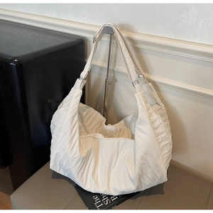 Detail of white pleated tote bag showing the vertical texture and silver metal rings