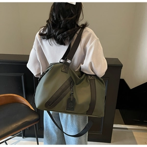 Detail of army green travel bag featuring durable nylon, wide straps, and decorative zipper
