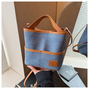 Détail du sac seau en denim et cuir marron montrant la texture et les coutures