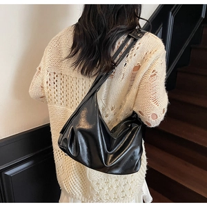 Detail shot of the glossy black synthetic leather and soft draping of the hobo bag