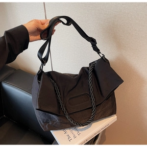 Detail of minimalist black nylon tote bag with braided handle and wide shoulder strap