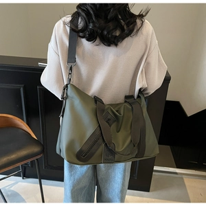 Olive green travel duffel with black shoulder strap and zipper pocket detail view