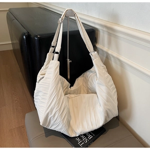 Detail of cream pleated hobo tote bag featuring adjustable strap and silver metal rings